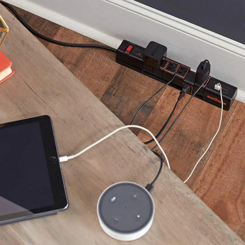 Rotating Surge Protector Power Strip With Six Swivel Outlets And Two USB Ports in use, charging devices on a wooden desk.