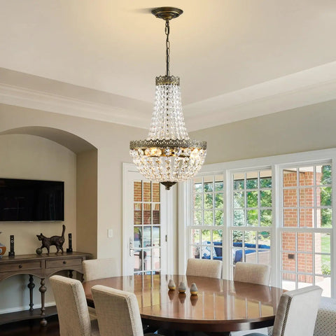 Elegant dining room featuring 4 Light French Empire Mini Crystal Chandelier With Antique Brass Finish over a wooden table.