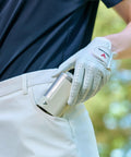 Golfer with gloved hand placing Laser Fit Golf Rangefinder With Slope Integration And Tournament Mode in pocket on course.