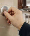Hand mounting metallic kitchen hook on tile wall near cooking utensils
