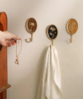 Super Clean Set Of Three Straight Up Vintage Wall Hooks With French Garden Floral Details And Classic Scalloped Metallic Hardware For Entryway Organizing And Cozy Bedroom Vibes, holding pearls and a scarf.