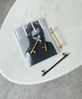 Gold and black cabinet pulls resting on a magazine and table, showcasing a variety of finishes and styles for interior design.