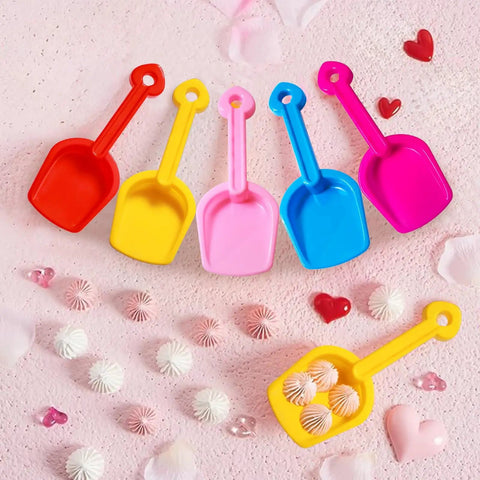 Five 7.8-inch colorful plastic shovels from 24 Pack Beach Shovels For Kids And Adults Heavy Duty Plastic Sand Toys Set on a pink surface
