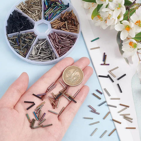 623 Pieces Glass Bugle Beads Set In Seven Dope Metallic Colors shown in hand and organizer, ideal for DIY jewelry making.