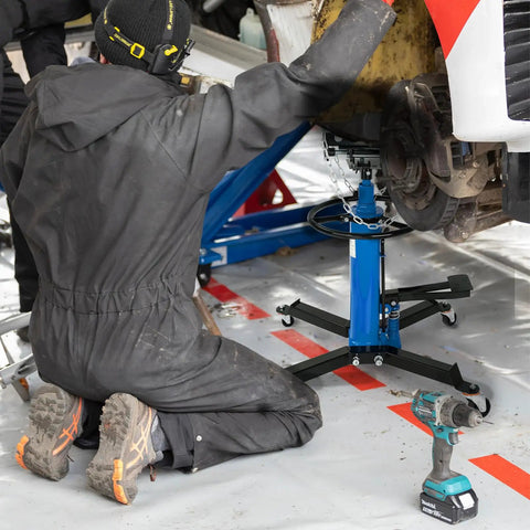 Kaflla High Lift Hydraulic Transmission Jack 1660 Lb With Foot Pedal being used by a mechanic kneeling beneath a vehicle.