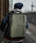 Person wearing green carry-on travel laptop backpack for airlines personal item with shoe compartment water resistant weekender bag