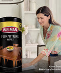 Clean Sweep Wood Polish And Cleaning Wipes For Furniture And Cabinets Lifts Off everyday grit on a dining table, with a woman using a microfiber cloth.