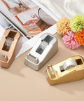 Heavy Duty Frosted Tape Dispenser Slick Non Skid Desk Holder Built Tough For One Hand Snipping Silver Plastic Organizer on a beige table.