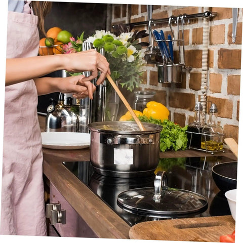 Person stirring pot on stove in kitchen with fresh vegetables and utensils visible