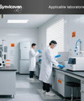 Two scientists in lab coats using equipment in a clean laboratory with floor mats and safety signs.
