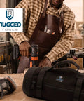 Craftsman working in workshop with Titan23XL Tool Roll And Organizer Bag nearby, heavy-duty canvas, quick grab top pocket visible.