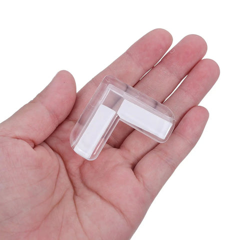 Hand holding a transparent Four Pack Soft PVC Table Corner Protector L Shaped Furniture Guard for tables and cupboards.