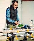 Man using Portable Folding Workbench With Vise And Eight Sliding Clamps Seven Level Height Adjustments Tiltable Extendable Tabletop