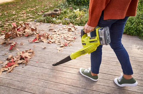 No Sweat Heavy Duty 18V Cordless Yard Leaf Blower With Comfy Overmold Grip cleaning leaves off a wooden patio.