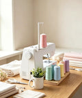 Large Thread Spool Stand For Sewing Machines keeps your pink thread stash organized next to a sewing machine with colorful spools.