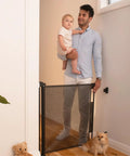 Parent and child using Retractable Baby Gate for Stairs and Doorways, 33 Inch Tall by 55 Inch Wide, Mesh Safety Gate, indoor setup