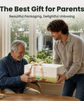 Two people exchanging a gift box in a bright and airy room with large windows and greenery.