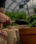 Person using Garden Scoop Shovel For Transplanting And Planting Stainless Steel Do It All Hand Digging Tool in potted plant