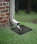 Low Profile Gutter Downspout Extender Kit With Flexible Catch Basin installed near a brick wall, draining water on grass