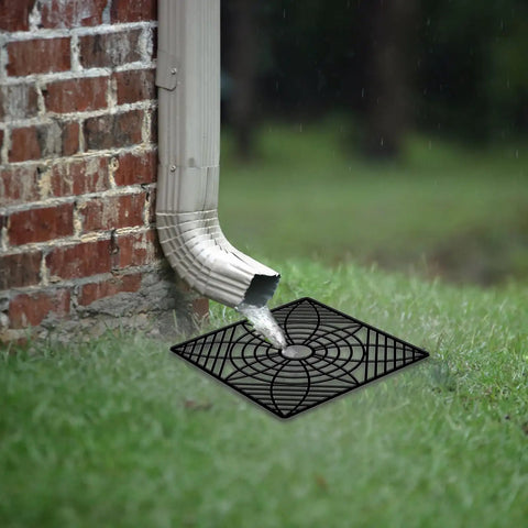 Low Profile Gutter Downspout Extender Kit With Flexible Catch Basin installed near a brick wall, draining water on grass