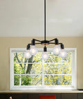 Five Light Modern Sputnik Chandelier in matte black over dining table with window background.