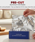 Hand pulling sheet from Heavy Duty Pre-Cut Aluminum Foil Sheets 12 x 10.75 Inches with Pop Up Dispenser for easy tear.