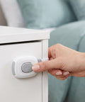 Hand using 10 Pack Child Safety Cabinet Locks Easy Install Plastic Latches For Cabinets Drawers Fridge Oven Toilet Kitchen Cupboards And Appliances Gray Durable Plastic Construction For Kid Proofing In Every Room on white cabinet with latch.