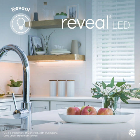 Stylish kitchen with chrome faucet, apples in a bowl, and natural light from window displaying Reveal LED lighting.