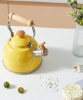 Yellow 1.6 Quart Tea Kettle With Cool Touch Wooden Handle Food Grade Stainless Steel Stovetop Teapot Whistling Kettle displayed on a table