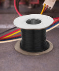 Flame Retardant Braided Cable Sleeve For Power Cords And Data Cables Breathable Mesh Wire Protector Tube on a spool with colorful wires.