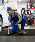 Anti Fatigue Standing Mat For Industrial Kitchens And Workshops, 2 Ft By 5 Ft, 15/16 Inch Thick Ergonomic Memory Foam Cushioned Floor Mat With Diamond Plate Texture, Heavy Duty Back And Leg Pain Relief For Long Shifts laying in garage.