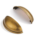 Three Inch Hole Center Antique Brass Cup Pulls Ten Pack Solid Metal Kitchen Cabinet Handles showing two cup pulls angled on white background.