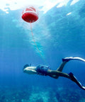 Snorkeler beneath the Red Dive Flag Inflatable Surface Marker Buoy For Scuba Diving Spearfishing And Boating with rope attachment