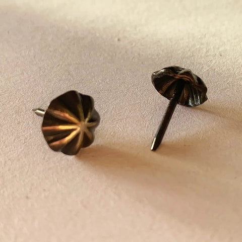 Close-up of Premium 7/16 Inch Upholstery Tacks For Furniture Fix Ups, sleek matte black decorative nailheads.