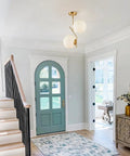 Two Light Glass Globe Pendant Light In Brushed Brass Gold Finish in a modern home entryway, large white globes hanging.
