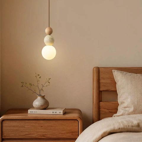 Wabi Sabi Travertine Pendant Light with Wood Ball & Milk Glass Shade hanging above a wooden nightstand in a cozy bedroom.