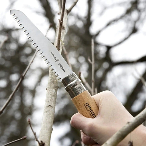Badass Lightweight Folding Saw For Weekend Campouts And Garden Grind Cuts Branches Fast With Razor Sharp Carbon Steel Blade Secure Virobloc Lock And Natural Beechwood Handle cutting through a branch.