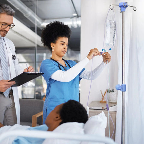 A nurse adjusts an IV on a Heavy Duty Stainless Steel Rolling IV Pole Stand With Built Tough Four Prong Holders And Quick Glide Casters.