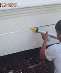 Man applying marine-grade gray polyurethane sealant adhesive 20 oz (600 mL) sausage, case of 12, to construction joint.