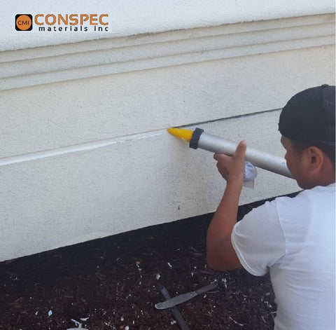 Man applying marine-grade gray polyurethane sealant adhesive 20 oz (600 mL) sausage, case of 12, to construction joint.