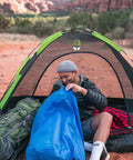 Person using Blue Camping Stuff Sack With Water Resistant Polyester For Sleeping Bags And Gear, 18 By 30 Inch
