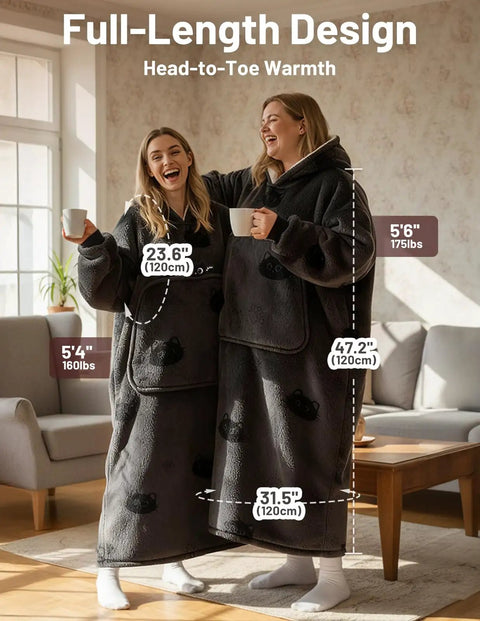 Two women wearing full-length wearable blanket hoodies for adults with flannel and sherpa lining, enjoying coffee at home.