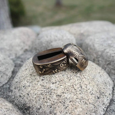 Antique Copper Tsuba And Fuchi Kashira Menuki Set For Samurai Sword Koshirae on rocks, detailed Japanese armor ornament.