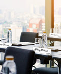 24 Pack Acrylic Name Plates For Desk 2x8 Inches Clear Slant Back Sign Holders on conference table with water bottles