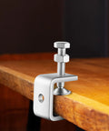 Installed front view of a 1-inch stainless steel mini C-clamp gripping a wooden workbench edge.