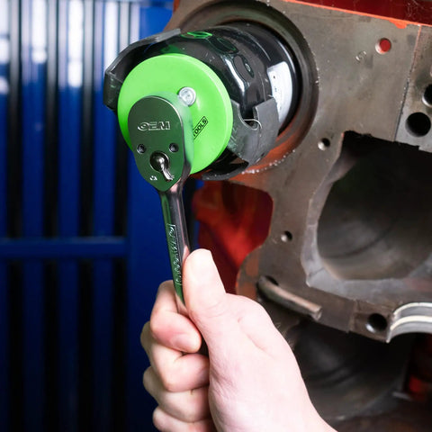 Hand using adjustable oil filter wrench for three and one eighth to three and seven eighth inch filters on car engine.