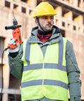 Look Sharp Hi Vis Safety Vest With Wraparound 360 Reflective Strips For Construction Crews Road Work Cycling And After Dark Jogging Activities Reliably worn by man holding drill