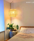 Plug In Pendant Light With Smooth Dimmable Switch And Handwoven Boho Rattan Shade over a cozy bedroom nightstand with plants.
