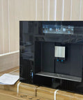 Next Level Built In Fully Automatic Coffee Maker With Glossy Black Glass Panel And Smart Touchscreen Interface on countertop.