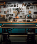 Workbench with Self Adhesive Work Bench Mat 23.5 X 200 Inch PU Floor Runner for Garage and Workshop, black mat surface, tools on pegboard.